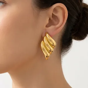 Close-up of elegant 18K gold plated fluted angel wing earrings on a model.
