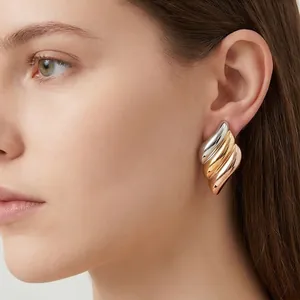 Detailed view of tri-color angel wing earrings worn on ear showing glossy metallic finish