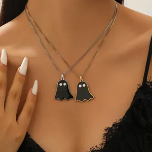 Close-up shot of trendy gold and silver ghost pendant necklaces with black enamel details