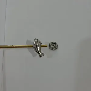 Detailansicht einer silberfarbenen Hand-Brosche mit einem Schmetterlingsverschluss