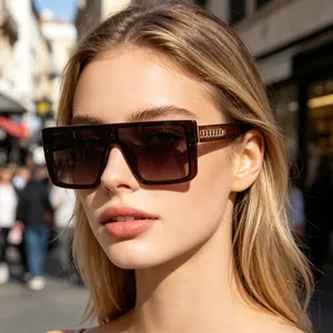 Stylish woman wearing oversized brown gradient square sunglasses in a bright city street