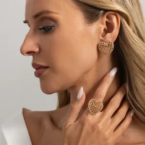 Detailed macro view of elegant golden hollow grid heart-shaped earring and matching ring set