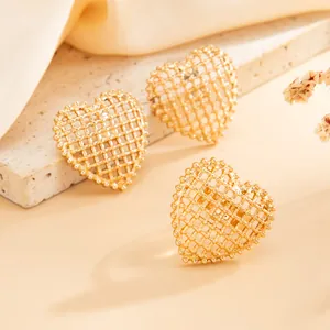 Macro view of gold heart-shaped jewelry with intricate hollow mesh grid design and warm lighting