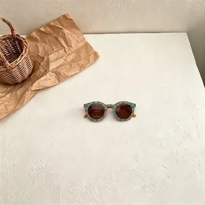 Detailed view of retro checkered sunglasses for children with teal and yellow pattern