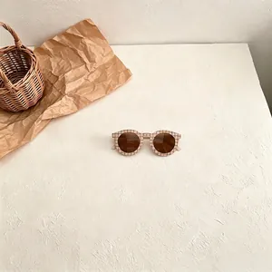 Close-up of stylish retro checkered children's sunglasses featuring brown lenses