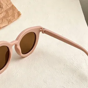 Detailed close-up showing the matte light pink frame and hinge of retro children's sunglasses