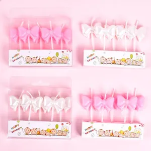 Detailed view of elegant pink and white bow-shaped birthday cake candles for parties.