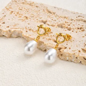 Close-up detail of minimalist gold knotted heart earrings with teardrop pearl drops