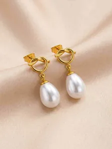 Macro view showing the intricate knotted design and smooth pearl texture of these gold earrings.