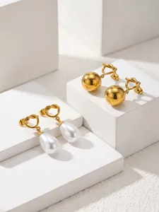 Detail view of gold-plated knotted stud earrings with pearl and golden bead drops.