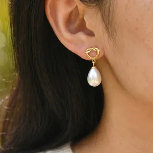 Close-up view of a 18K gold plated stainless steel knot earring with a teardrop pearl