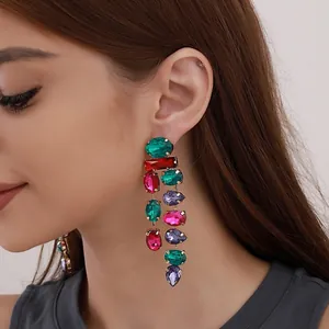 Close-up of colorful gemstone chandelier earrings worn by a model in a studio