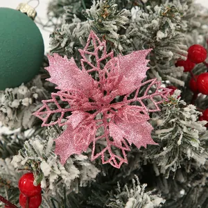 Close-up of a 9cm pink glittery hollow poinsettia flower on a snowy Christmas tree.