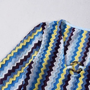 Detail of colorful zigzag knit dress with V-neckline and gold ring buckle feature.