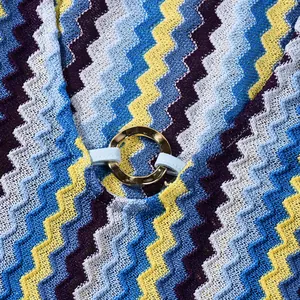 Close-up detail of colorful zigzag knit dress with golden metal ring buckle hardware