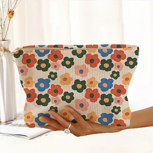 Detail of hand holding a corduroy cosmetic bag with colorful hand-drawn floral patterns