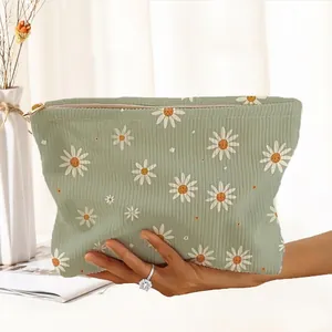 Detailed view of the sage green corduroy makeup bag featuring a white daisy floral print