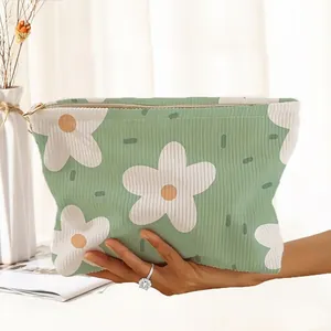 Detailed view of the corduroy fabric and floral print on a green zipper makeup bag
