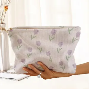 Close-up shot of a purple tulip floral printed corduroy zipper pouch held by hand