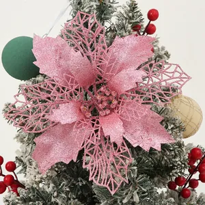 Close-up of pink glittery poinsettia flower decoration on a snowy Christmas tree