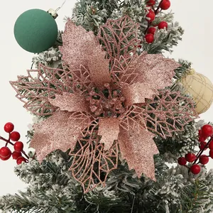 Detailed macro of rose gold glitter poinsettia flower on snowy Christmas tree branch