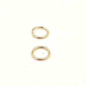 Close-up of two golden electroplated copper open jump rings for DIY jewelry making.