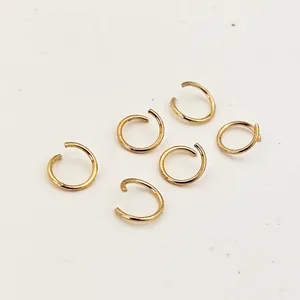 Close-up macro view of six gold-plated copper open jump rings for DIY jewelry making