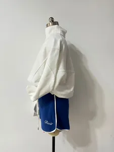 Side view of white half-zip sweatshirt and blue athletic shorts set