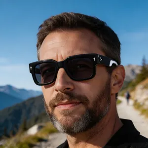 Close-up of a stylish man wearing retro black square sunglasses in outdoor nature.