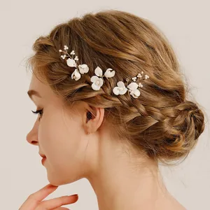 Handmade bridal hair pins featuring white ceramic flowers, crystal accents and pearls