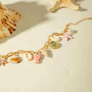 Detail macro view of Bohemian gold anklet with seashell and pink ceramic fish charms.