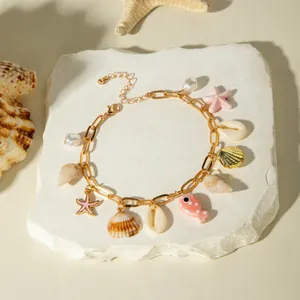 Detailed view of bohemian gold anklet with natural sea shells and pink ceramic fish charms