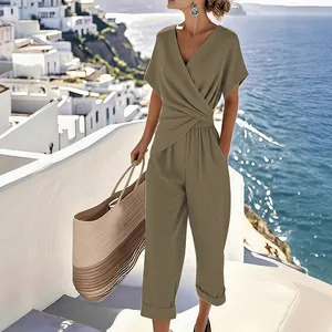 Full view of women's olive green V-neck wrap jumpsuit against a scenic coastal background