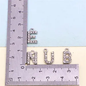 Close-up of sparkling rhinestone alphabet charms with a ruler for scale