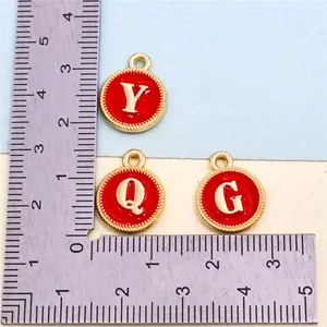 Red enamel alloy alphabet charms shown next to a metal ruler for size reference