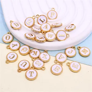 Close-up view of 26 white enamel alphabet charms with gold-tone borders for DIY jewelry.