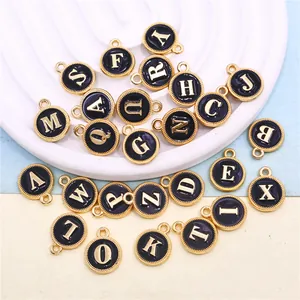 Detailed view of 26 black enamel gold initial letter charms for DIY jewelry making.
