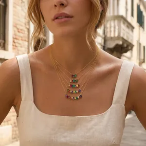 Detail shot of a model wearing a vintage multi-layer gold necklace with colorful zircon