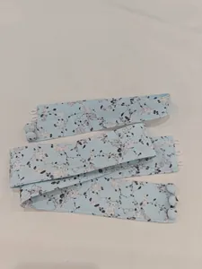 Detailed macro view of light blue floral print fabric accessory with button closures