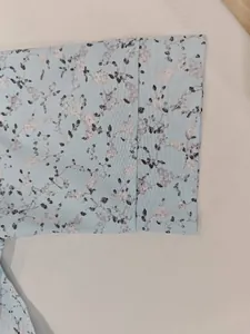 Close-up of elegant floral print and stitching on light blue dress sleeve