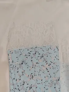Detailed macro view of light blue floral print fabric with white eyelash lace trim detail