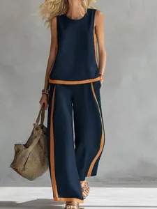 Detail view of sleeveless navy top and wide-leg pants with orange contrast stripes.