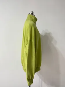 Detalle de una sudadera con media cremallera verde lima con cuello y puños de canalé.
