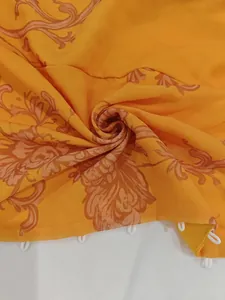 Gros plan sur un tissu jaune imprimé floral vintage avec des boucles de boutons blanches.