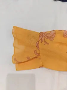 Vue détaillée de la manche évasée d'une robe en mousseline orange au motif floral rétro
