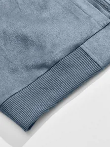 Close-up detail of a blue suede jacket featuring ribbed hem texture and fine stitching.