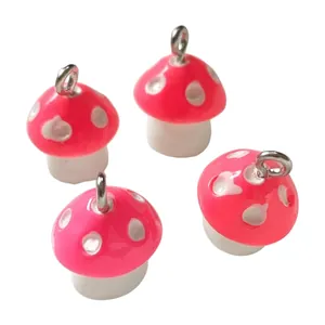 Detailed view of pink resin mushroom charms with white polka dots for jewelry making