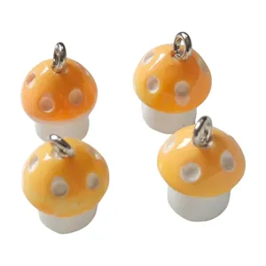 Detailed macro view showing four orange and white resin mushroom charms with silver loops