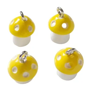 Close-up of four yellow mushroom resin charms with white spots for DIY jewelry