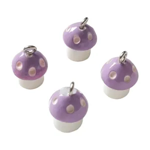 Close-up of four purple resin mushroom charms with silver loops for DIY jewelry.